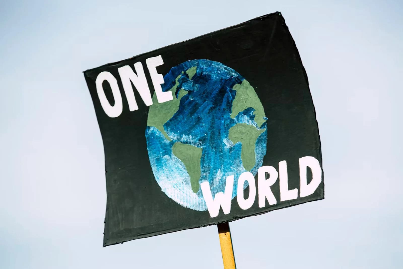 Un cartello con il pianeta Terra e la scritta One World