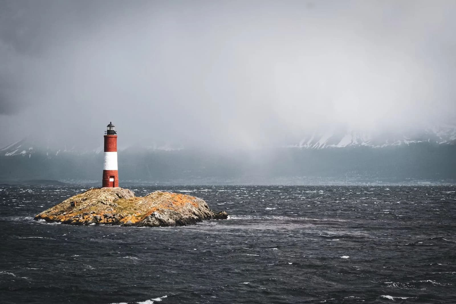 Faro in mare aperto tra vento, freddo e montagne